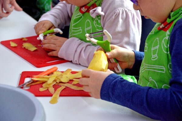Dzieci obierają ziemniaki w prywatnym przedszkolu.