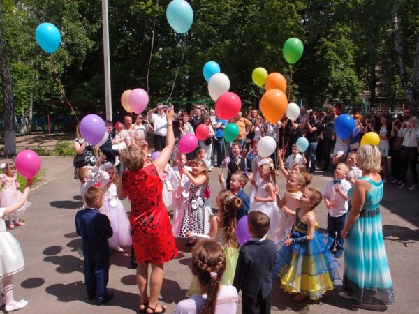 Dzieci wypuszczają balony w ramach uroczystości w prywatnym przedszkolu.