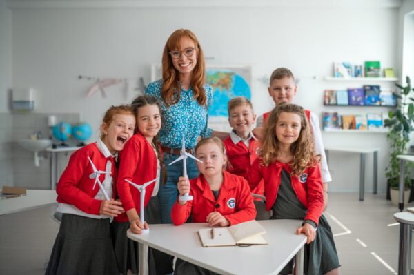 Grupa dzieci z nauczycielką w klasie w prywatnej szkole podstawowej.